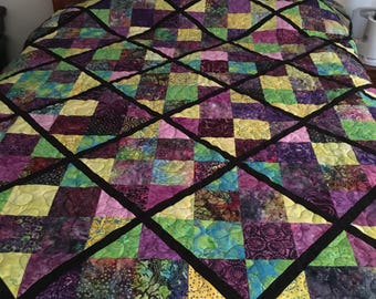 bright colorful batik farics are combined together and bordered with black in this pne of a kind queen size quilt.